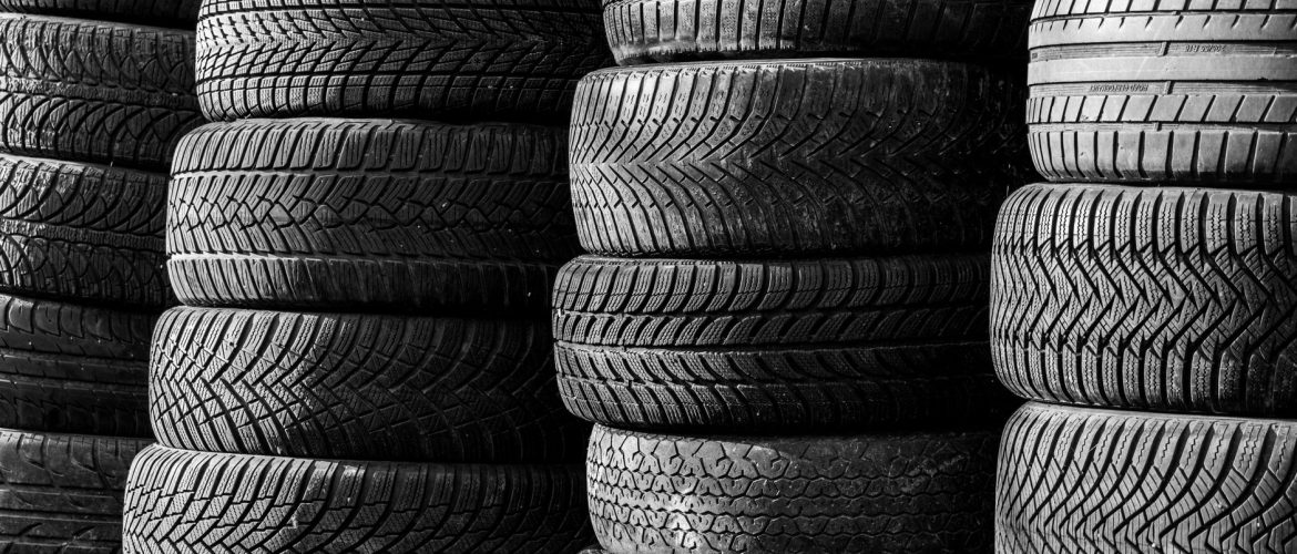 Black and white image of stacked vehicle tires showcasing various tread patterns.