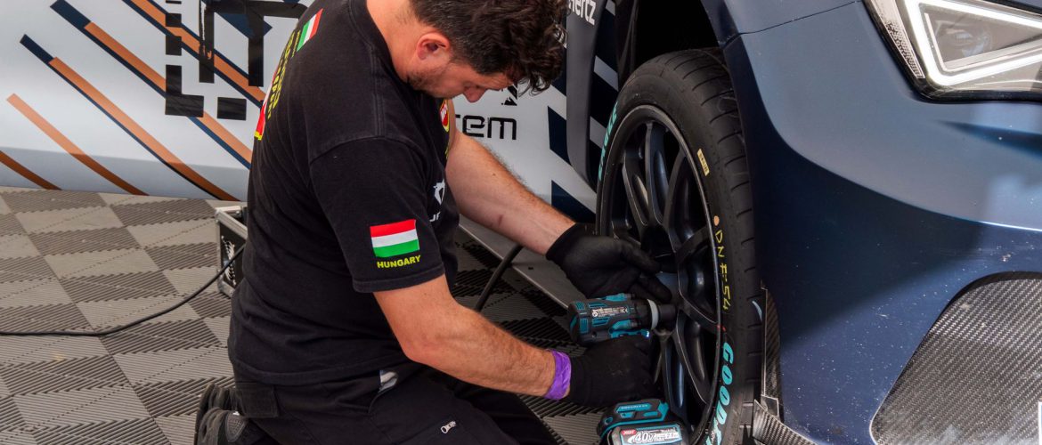 Mechanic fixing a car tire in a service station using power tools. Professional car maintenance.