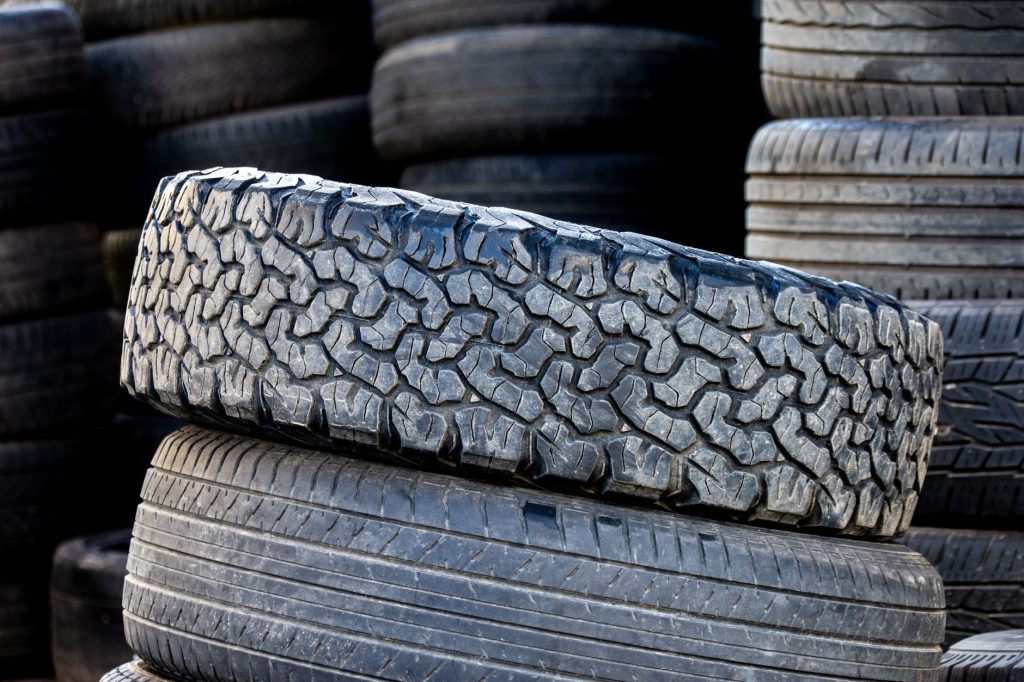 Açık havada üst üste dizilmiş otomobil lastiklerinin, dayanıklı diş desenlerini sergileyen yakın çekim görüntüsü.