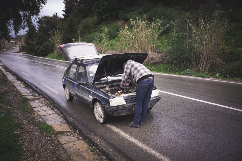 Tabarka'da, yağmurlu bir yolda bir bireyin acil yol kenarı araç bakımı yaptığı an.