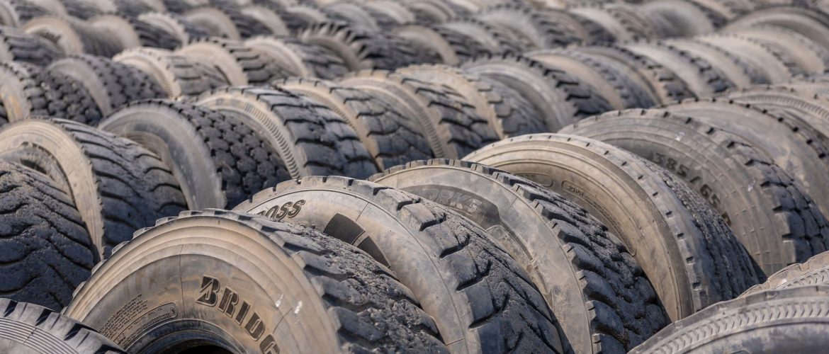 A detailed view of numerous stacked used tires in an outdoor industrial environment.