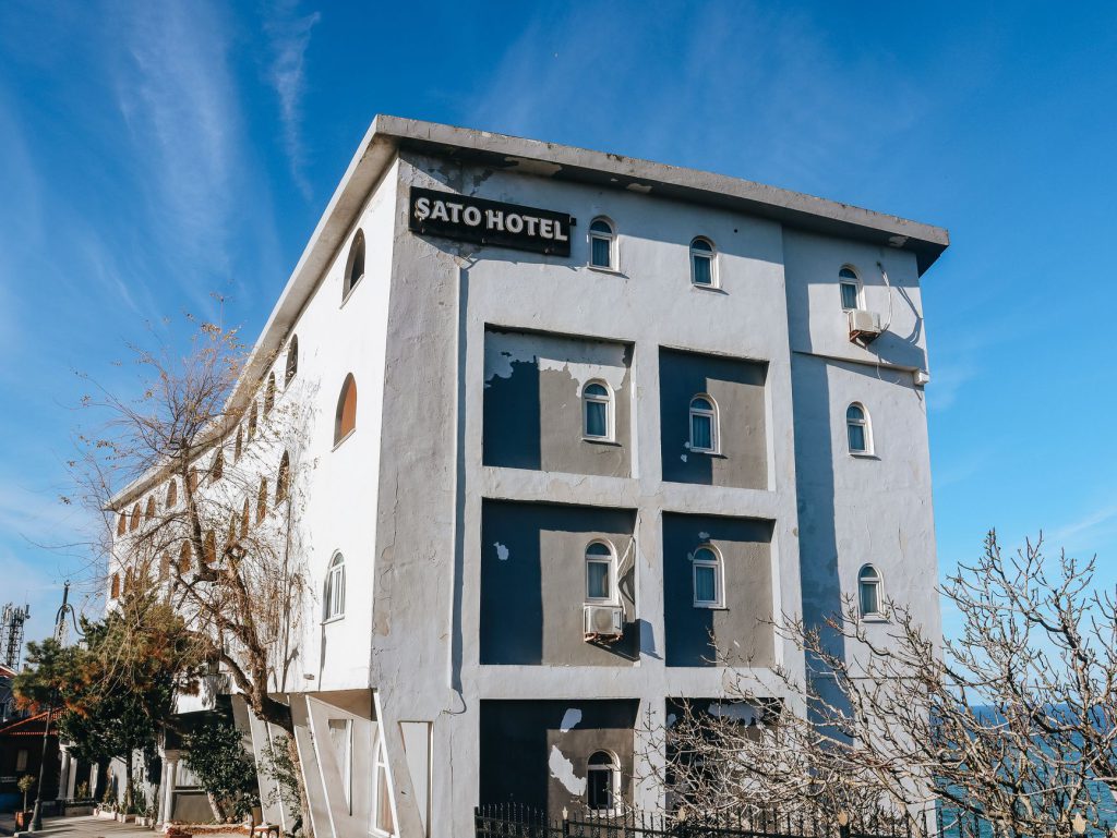 Parlak mavi gökyüzünün altında dökülen boyasıyla Sato Otel binası, kentsel mimariyi sergiliyor.
